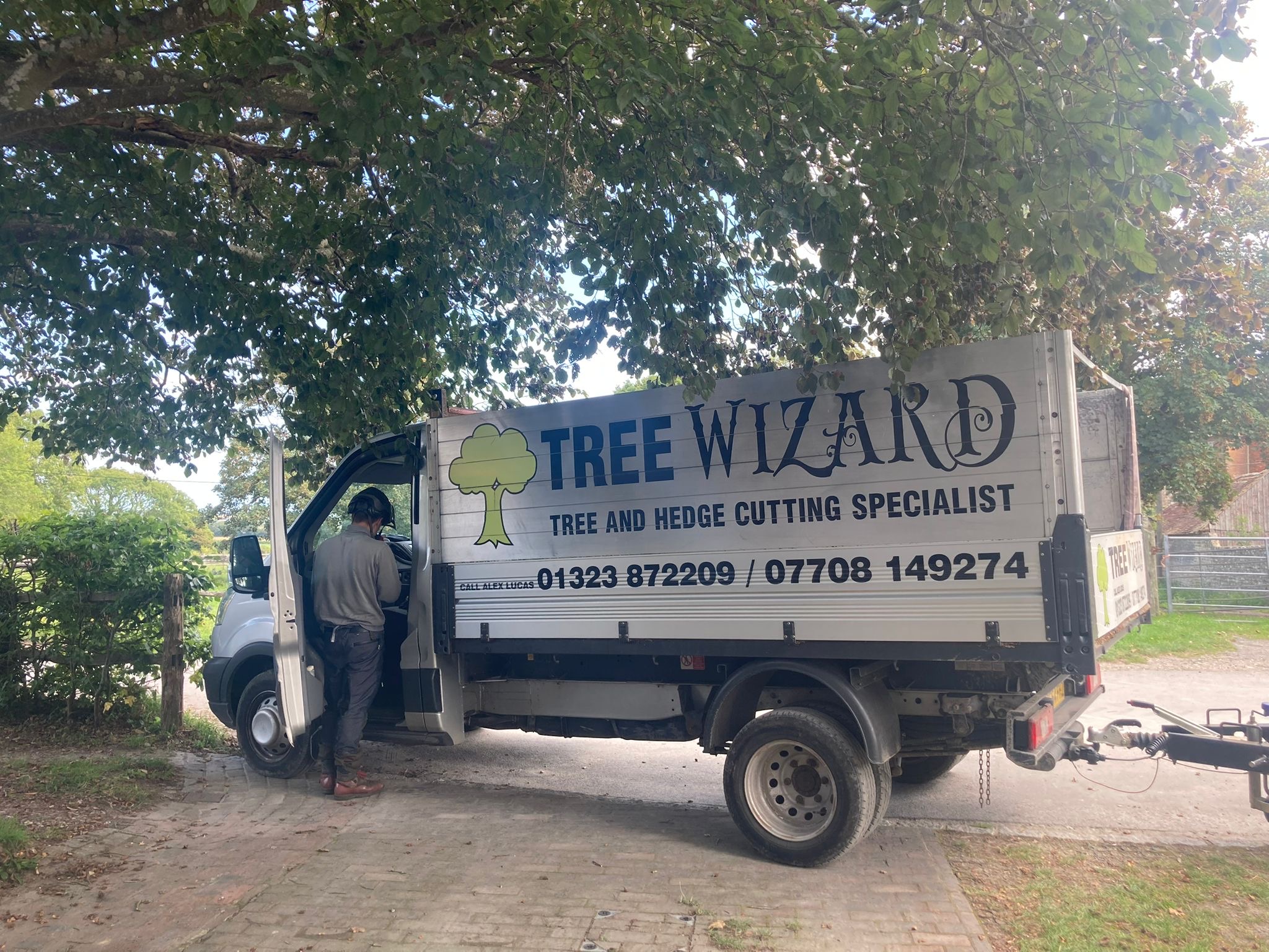 The Tree Wizard tipper van parked under a tree canopy